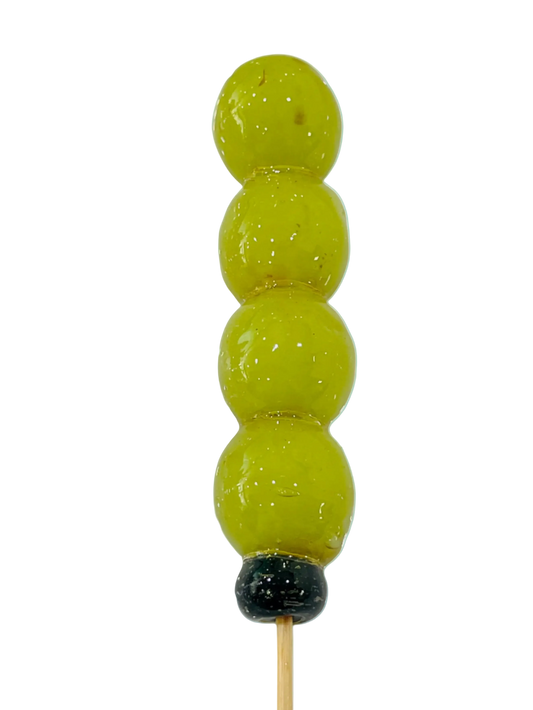 sugar glazed green grapes on a stick on a light background