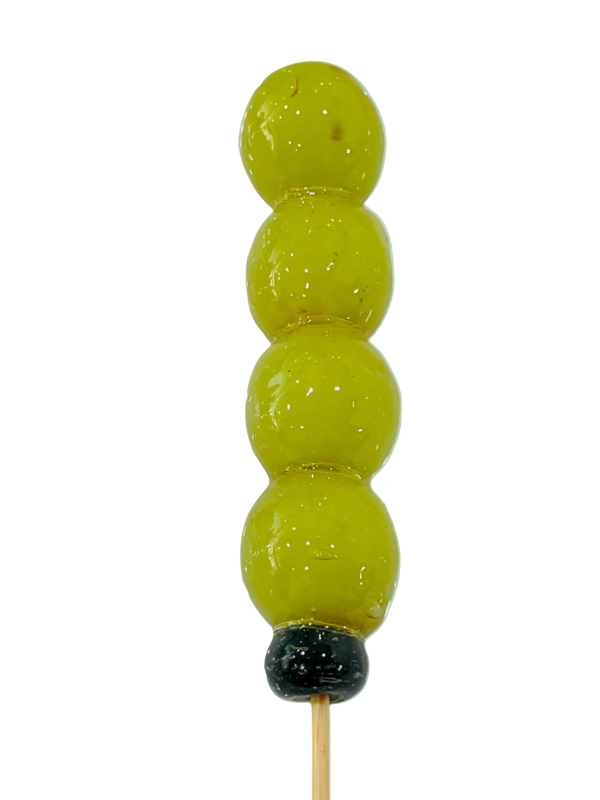 sugar glazed green grapes on a stick on a light background