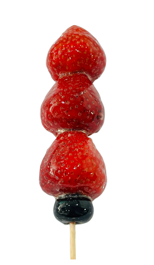 Sugar glazed strawberry skewer with a blueberry on a light background